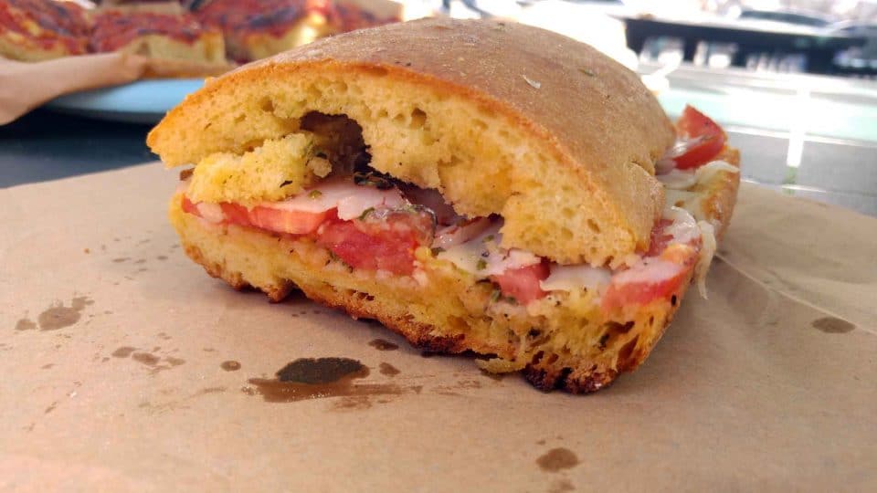 pane cunzato, crispy bread, tomato, cheese, anchovy and, of course oil: a street food panino