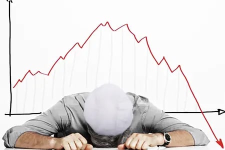 person laying down on desk with failure graph in background