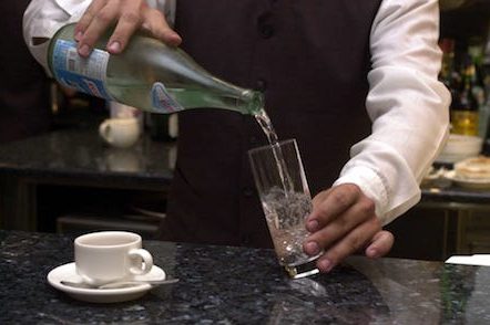 pouring a glass of water at the bar, to go along with coffee